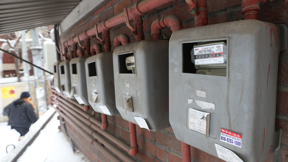 2025 겨울 난방비 절약 가이드를 보며 난방 온도를 조절하는 사람들